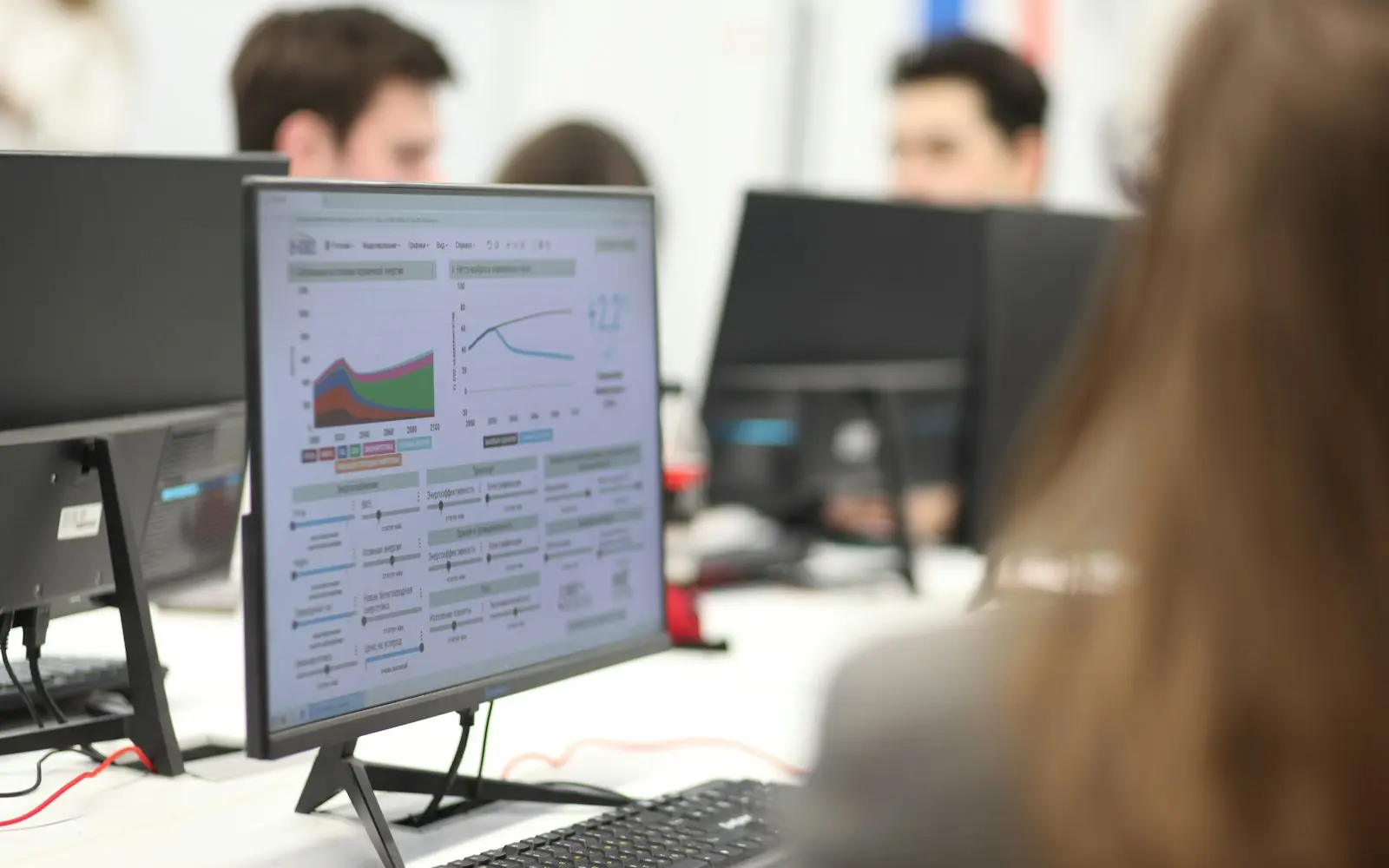 Analysts at desks with a monitor showing data charts and model curves