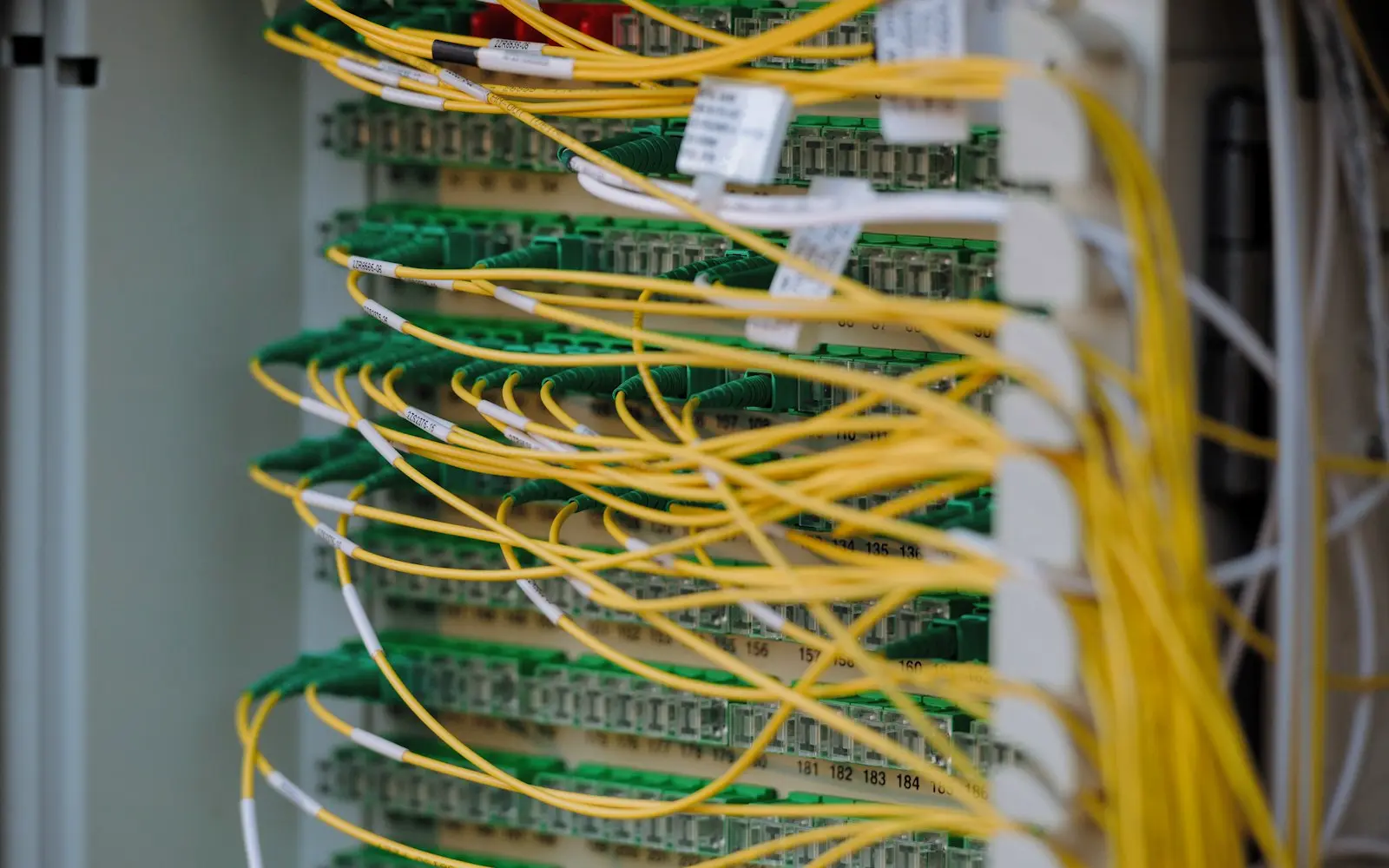 Network patch panel with yellow fibre cables connected in a server rack