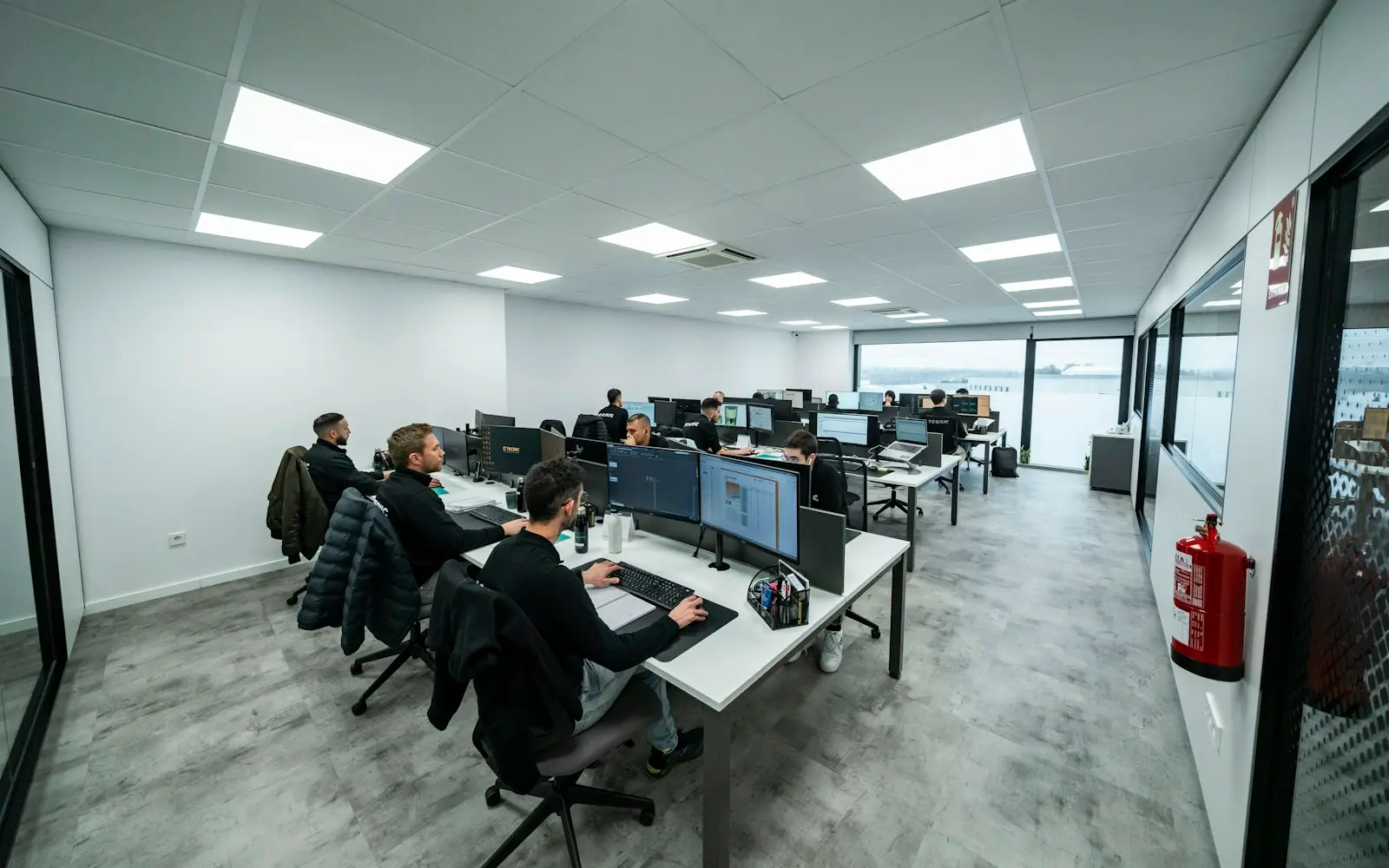 Developers working at rows of monitors in a bright open office