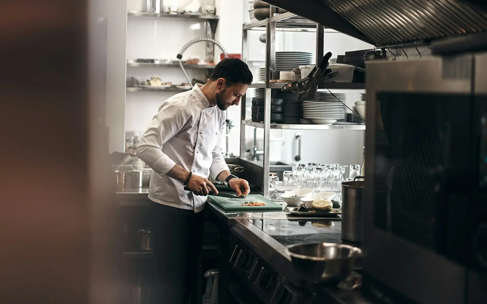 Chef in a white coat chopping vegetables in a professional kitchen