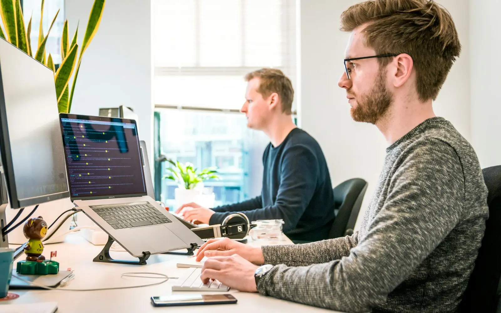Two developers at laptops in a sunlit open office