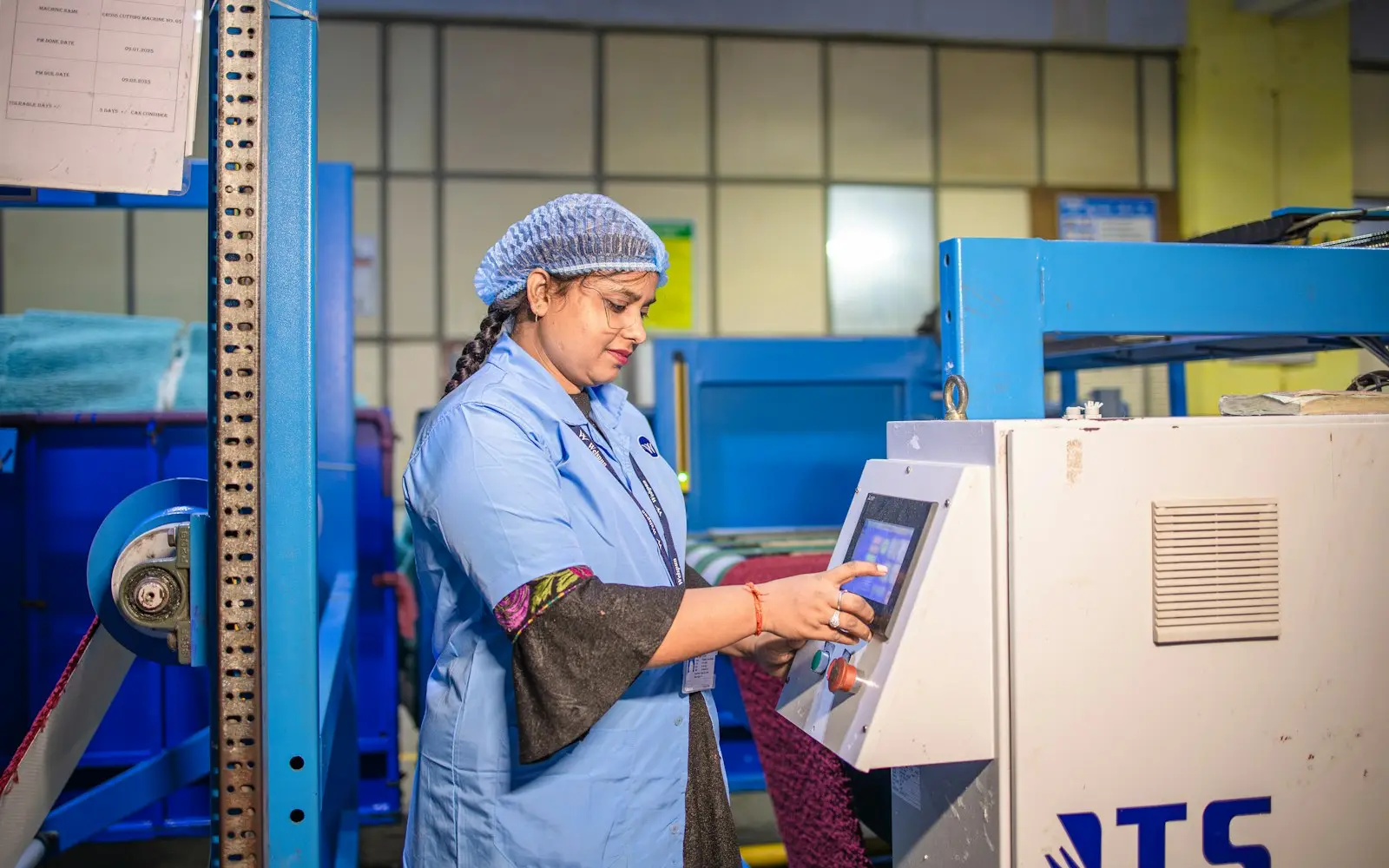 Factory worker operating a touchscreen control panel on a production machine