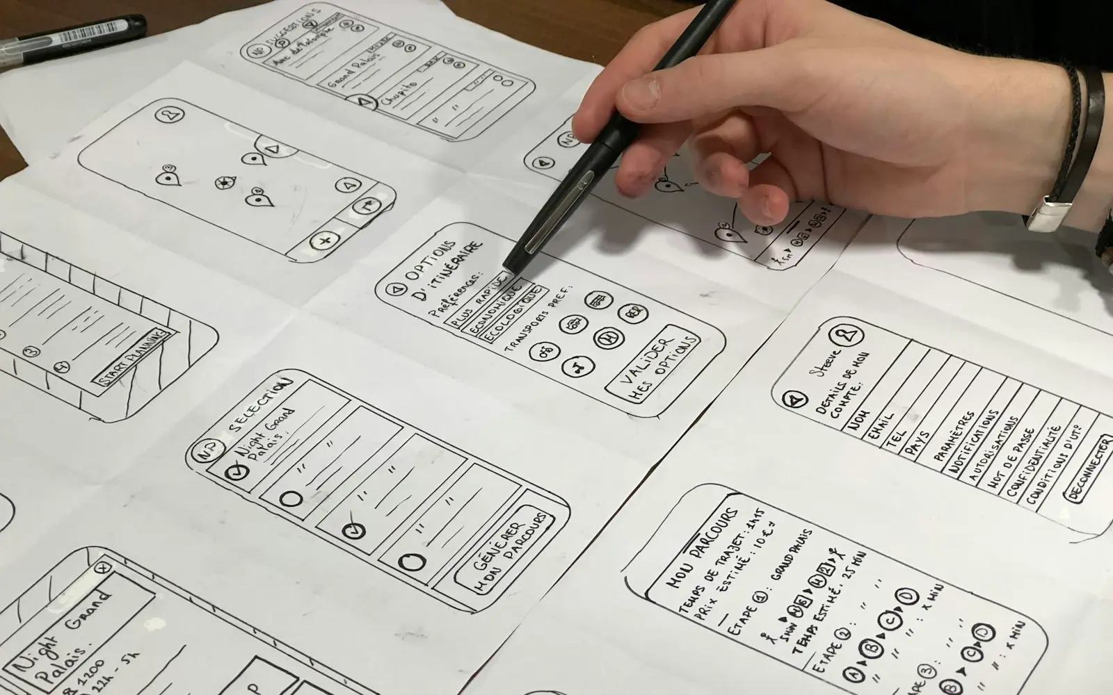 Hand sketching paper wireframes of mobile app screens