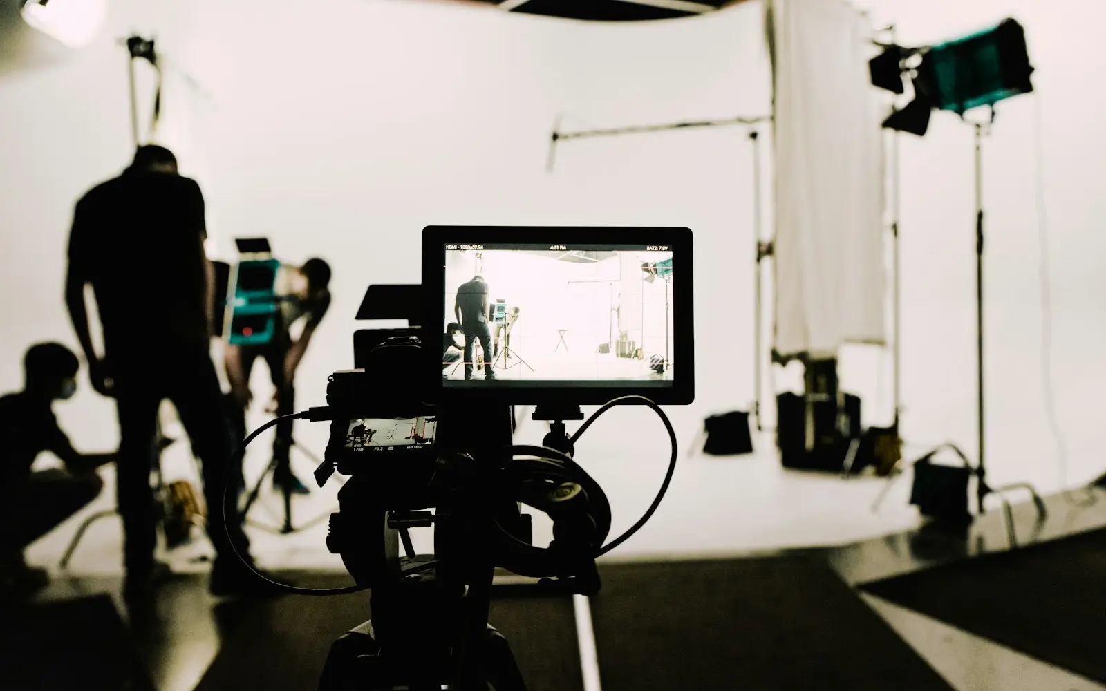 Film crew with a cinema camera and monitor on a white-cyclorama studio set