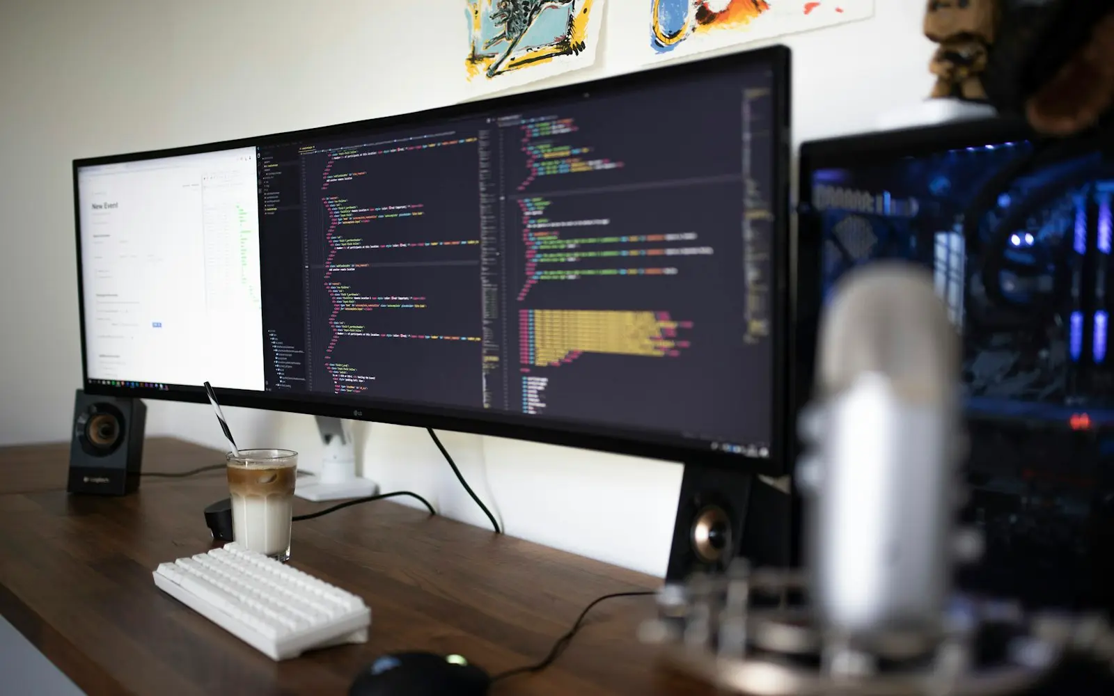 Ultrawide monitor showing code on a tidy desk with a microphone