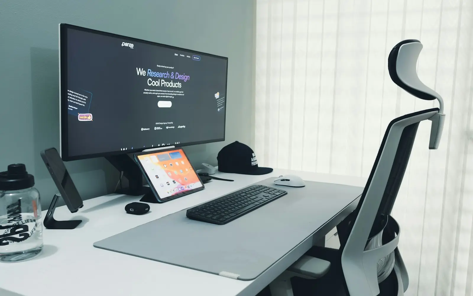 Wide monitor showing a website on a bright desk with an ergonomic chair
